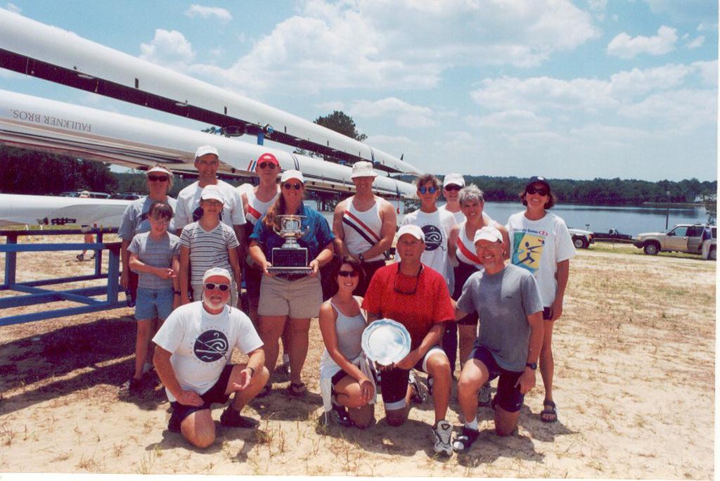 Nevin posing with group while holding trophies